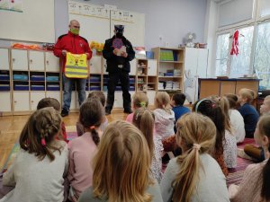 policjant pokazuje dzieciom znaki drogowe podczas rozmowy na temat bezpieczeństwa w ruchu drogowym