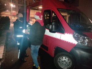 policjant oraz Młodzieżowa Drużyna Pożarnicza podczas wypakowywania darów z samochodu