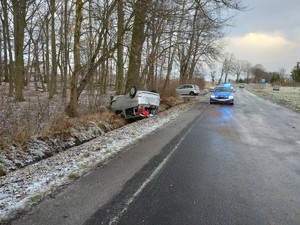 pojazd toyota znajdujący się w rowie, leży na dachu, obok radiowóz