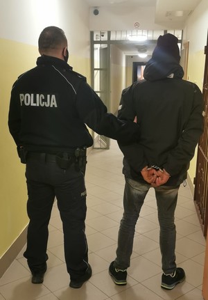 zatrzymany z kajdankami na ręce trzymane z tyłu w korytarzu
