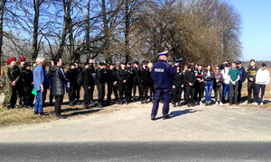 policjant podczas tłumaczenia obsługi urządzenia do pomiaru prędkości, w tle widoczna młodzież