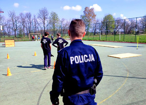 policjant przyglądający się i dopingujący młodzież, która brała udział w policyjnym torze przeszkód
