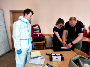 policjant pobiera od studentki ślady linii papilarnych na kartę daktyloskopijną