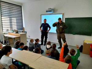 policjant ze strażnikiem leśnym podczas spotkania w sali szkolnej z uczniami