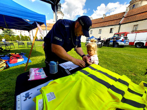policjant z dziewczynką stoi przed stolikiem do odciskania linii papilarnych