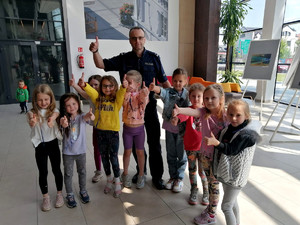 Policjant stoi z grupą przedszkolaków, hol Miejskiej biblioteki publicznej w Piotrkowie Trybunalskim
