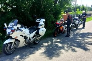 policjant stojący przy policyjnym motocyklu, obok stoi motocyklista zatrzymany do kontroli