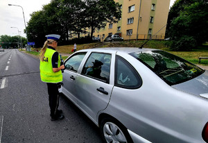 policjantka stojąca obok kontrolowanego pojazdu