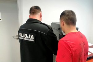 technik kryminalistyki pobiera odciski palców od zatrzymanego
