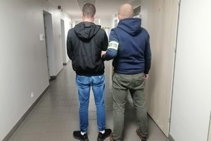 policjant prowadzi zatrzymanego