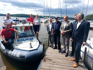 Komendant Miejski Policji wraz z samorządowcami, ratownikami WOPR oraz policjantami przy łodzi policyjnej.