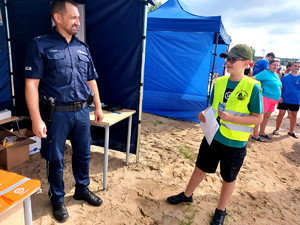 Policjant wraz z chłopcem przed policyjnym namiotem.