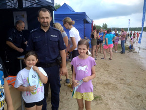 Policjant z dziećmi przed policyjnym namiotem.