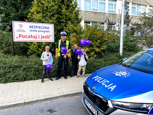 Policjant z dziećmi pod jedną ze szkół podstawowych podczas działań bezpieczna droga do szkoły.