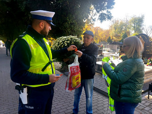 Policjanci podczas przekazywania odblasków w rejonie cmentarzy.