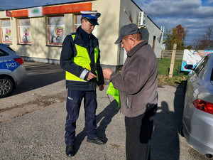 Policjanci podczas przekazywania elementów odblaskowych.