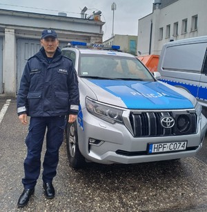 policjant stoi przy radiowozie