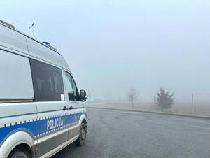 policyjny radiowóz, w tle ograniczona widoczność spowodowana przez mgłę.