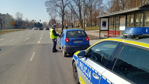 Policjant podczas kontroli drogowej wręczający kwiaty kobiecie.