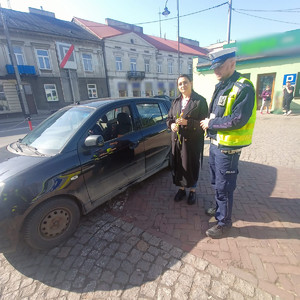 Policjant podczas kontroli drogowej wręczający kwiaty kobiecie.