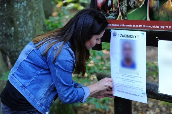 Kobieta wieszająca ogłoszenie o zaginięciu.