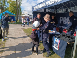Policjanci podczas pikniku wraz z odwiedzającymi policyjne stoisko.