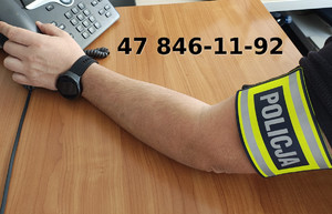 Ręka policjanta przy telefonie.