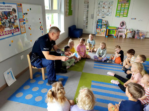 Policjant wraz z dziećmi podczas prelekcji w przedszkolu.