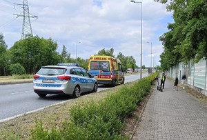 Policjantka na miejscu zdarzenia, obok policyjny radiowóz.