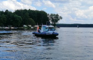 Policyjni wodniacy na łodzi motorowej.