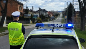 Policjant ruchu drogowego przy radiowozie.
