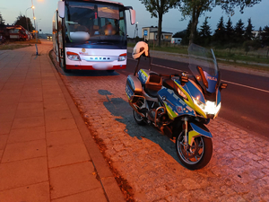 policyjny motocykl przed autokarem.