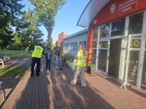 Policjanci wraz z przedstawicielem WORD podczas przekazywania elementów odblaskowych dzieciom przed wejściem do szkoły w Gomulinie.