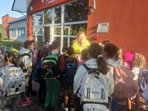 Policjanci wraz z przedstawicielem WORD podczas przekazywania elementów odblaskowych dzieciom przed wejściem do szkoły w Gomulinie.