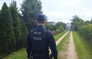 Policjant podczas kontroli terenów ogródków działkowych.