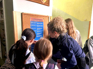 Policjantka podczas wizyty w szkole wieszająca plakaty informujące o numerach wsparcia.