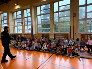 Policjant wraz z dziećmi podczas prelekcji w szkole podstawowej.