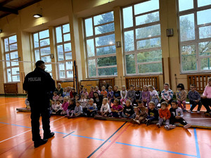Policjant wraz z dziećmi podczas prelekcji w szkole podstawowej.