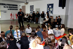 Policjant wraz z uczniami podczas prelekcji w szkole podstawowej.