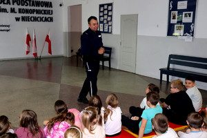 Policjant wraz z uczniami podczas prelekcji w szkole podstawowej.
