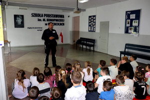 Policjant wraz z uczniami podczas prelekcji w szkole podstawowej.