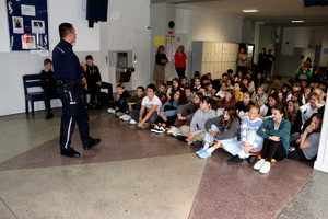 Policjant wraz z uczniami podczas prelekcji w szkole podstawowej.