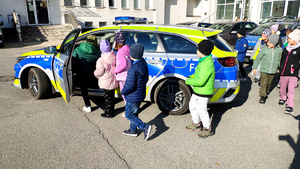 Policjantka wraz z dziećmi podczas prelekcji na dziedzińcu komendy.