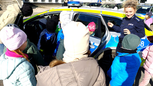Policjantka wraz z dziećmi podczas prelekcji na dziedzińcu komendy.