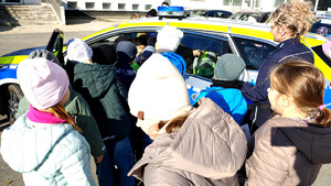 Policjantka wraz z dziećmi podczas prelekcji na dziedzińcu komendy.