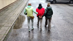 Policjanci prowadzący zatrzymanego przez dziedziniec komendy.