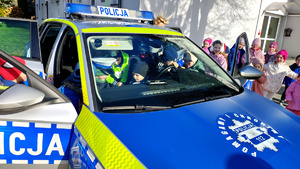 Przedszkolaki wsiadające do radiowozu.