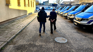 Policjant z zatrzymanym na dziedzińcu komendy.