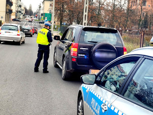 Policjantka stojąca przy aucie podczas kontroli drogowej.