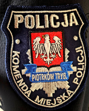 Emblemat umieszczony na mundurze z napisem Policja, Komenda Miejska Policji w Piotrkowie Trybunalskim.